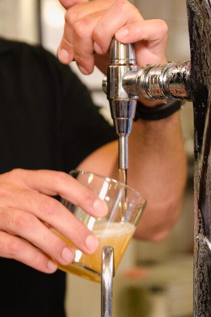 Foto un hombre sirviendo una cerveza muy fría en un vaso.