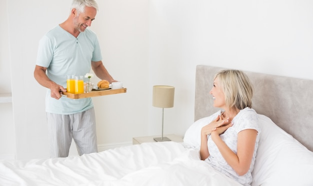 Hombre sirviendo desayuno de mujer en la cama