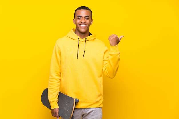 Hombre skater afroamericano apuntando a un lado para presentar un producto