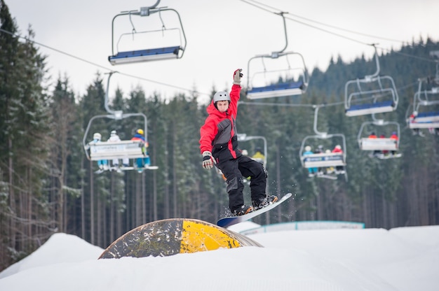 Hombre en el snowboard saltando por encima de un obstáculo en día de invierno