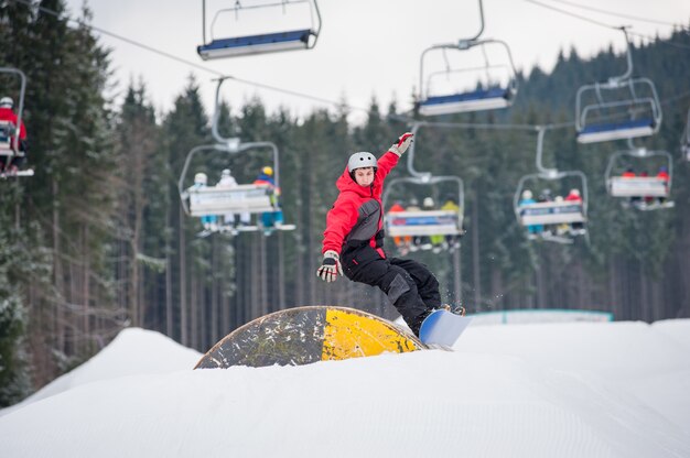 Hombre en el snowboard saltando por encima de un obstáculo