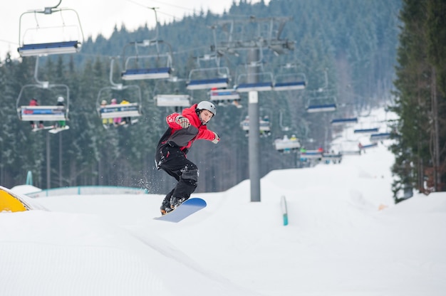 Hombre en el snowboard saltando sobre la pendiente en día de invierno