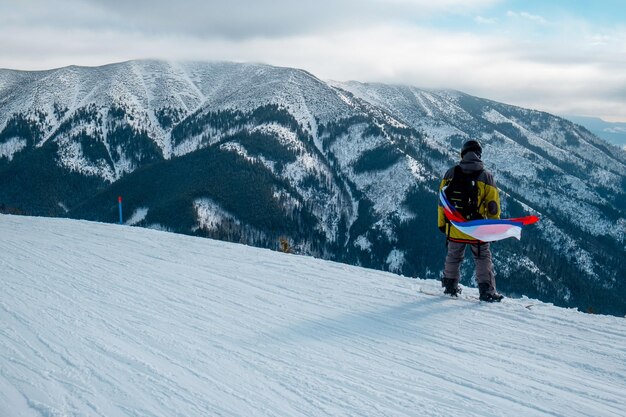 Hombre snowboarder con bandera de eslovaquia en la pendiente de la estación de esquí