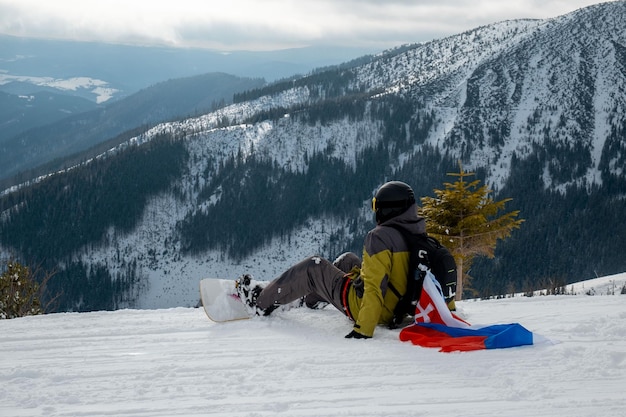 Hombre snowboarder con bandera de eslovaquia en la pendiente de la estación de esquí