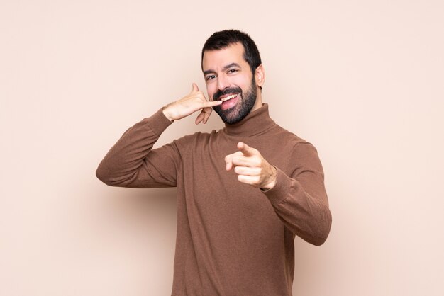 Hombre sobre aislado haciendo gesto de teléfono y apuntando hacia delante