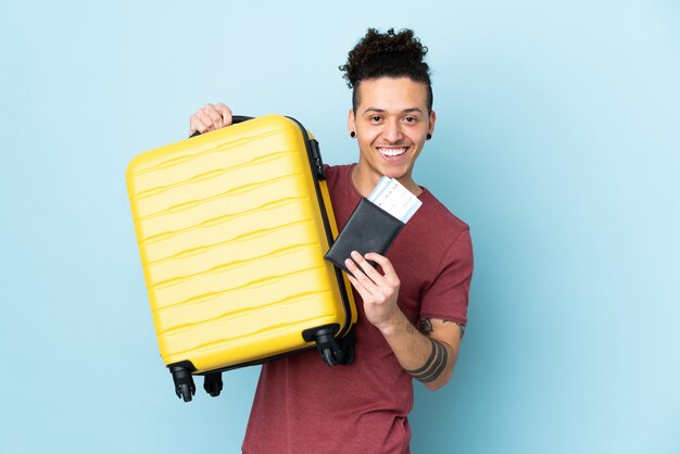 Hombre sobre azul aislado en vacaciones con maleta y pasaporte