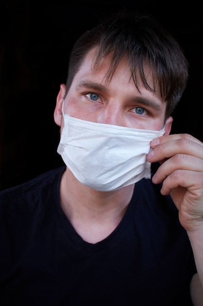 Hombre sobre fondo oscuro con una máscara médica. Protección contra virus, bacterias y enfermedades.