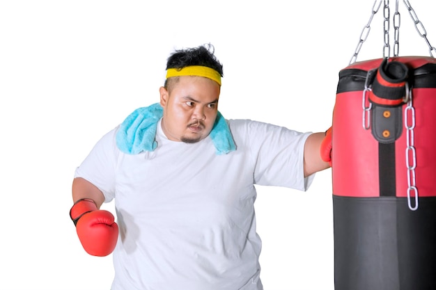 Hombre con sobrepeso golpeando una bolsa de boxeo en el estudio