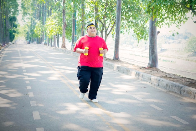 Hombre con sobrepeso trotando con pesas en el parque