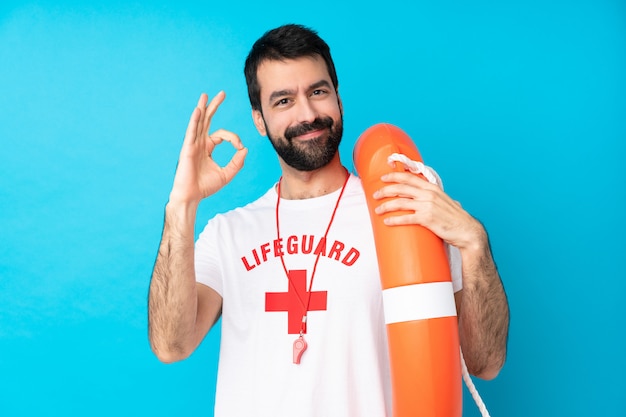 Foto hombre de socorrista sobre pared azul aislado mostrando signo bien con los dedos