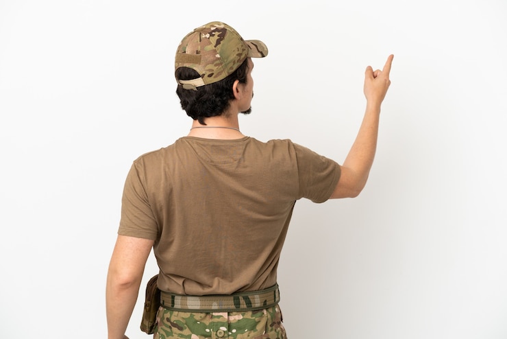 Foto hombre soldado aislado sobre fondo blanco apuntando hacia atrás con el dedo índice