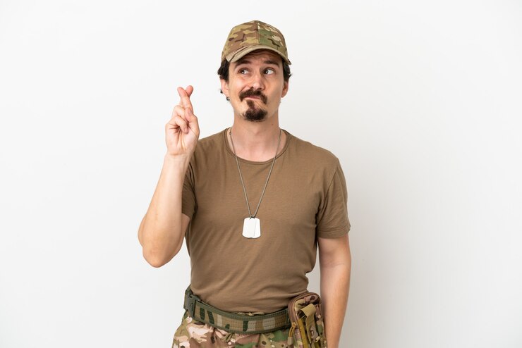 Foto hombre soldado aislado sobre fondo blanco con los dedos cruzando y deseando lo mejor