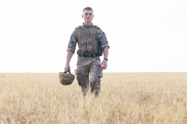 Hombre soldado de pie contra un campo. Retrato de feliz soldado militar en el campo de entrenamiento. Soldado del Ejército de Estados Unidos en la Misión. guerra y concepto emocional.