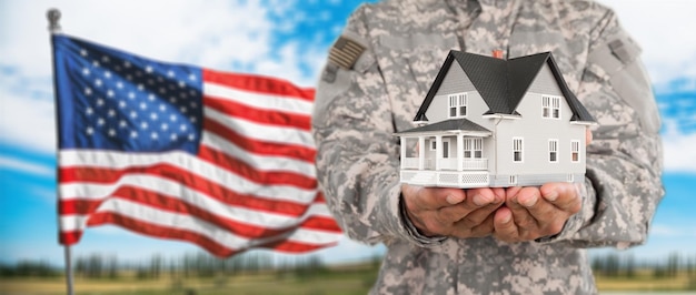 Hombre soldado sosteniendo un modelo de casa