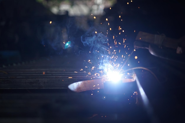 Un hombre soldando una pieza de metal con una luz azul.