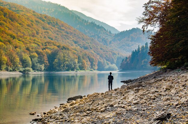 Hombre solitario en las montañas junto al lago en otoño