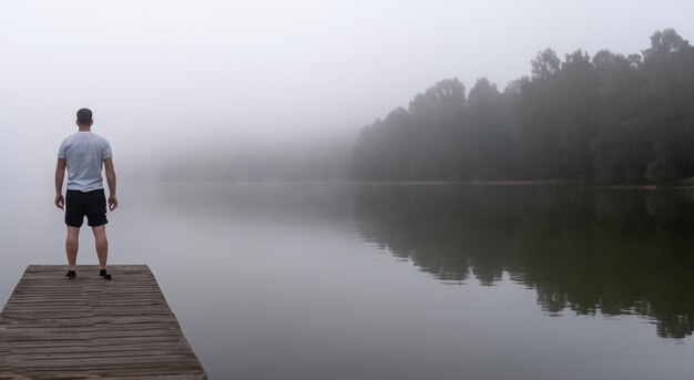 Foto hombre solitario en un muelle brumoso