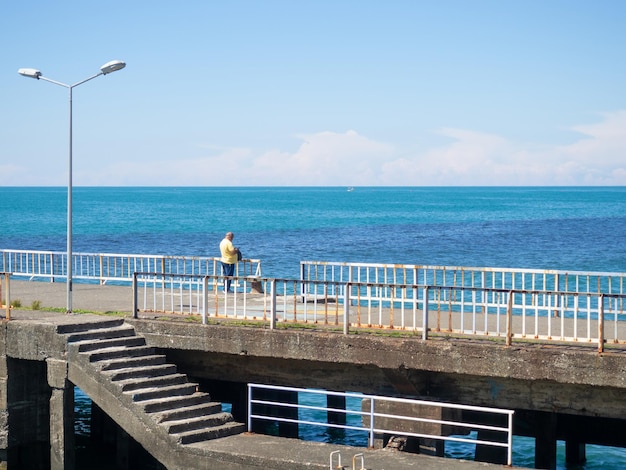 Hombre solitario en el muelle Descanso en la orilla del mar Escape de la vida cotidiana