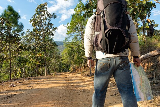 Hombre solitario con pantalones vaqueros y botas de cuero caminando por el camino cubierto de rocas.