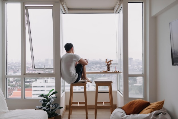 Hombre solitario sentado junto a las ventanas en la habitación Concepto de solitario corazón roto