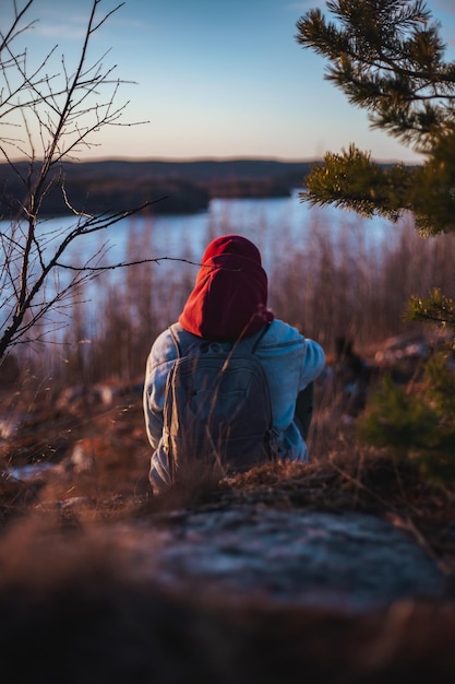 Hombre solitario sentado y mirando la puesta de sol detrás de un río dramático y solitario