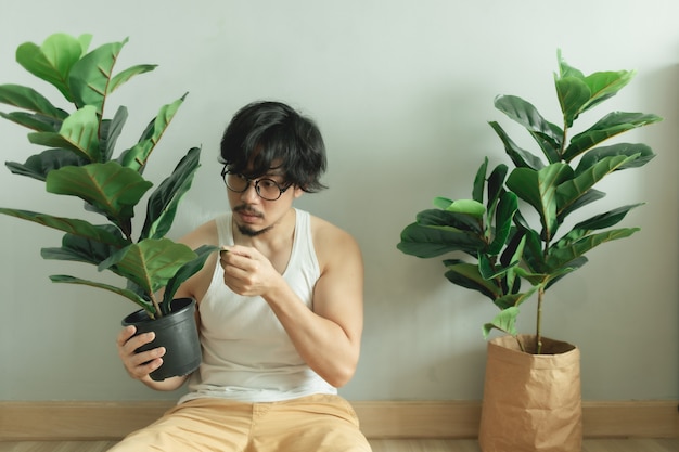 Hombre solitario siendo amigo de su planta de árbol en el apartamento.