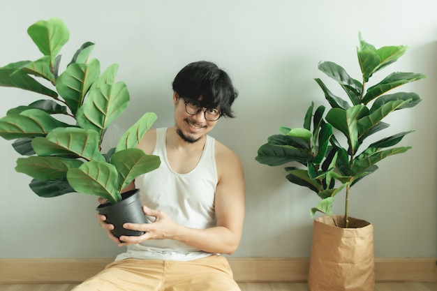 Hombre solitario siendo amigo de su planta de árbol en el apartamento.