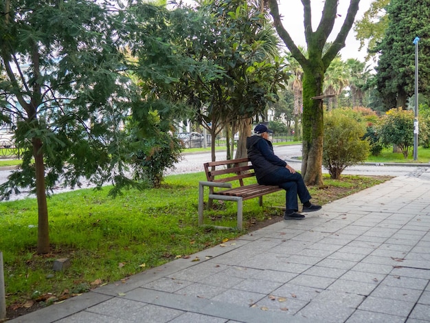 Un hombre solitario se sienta en un banco del parque entorno urbano El hombre se sienta sobre su espalda calles de Batumi