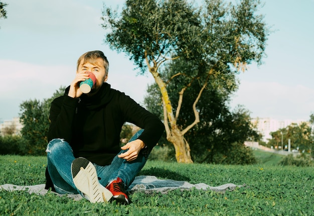 Foto hombre solitario, solo, de mediana edad tomando café en el parque. concepto de soledad, distanciamiento social y autoafirmación. concepto de salud mental, conexión con la naturaleza.