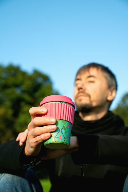 Hombre solitario, solo, de mediana edad tomando café en el parque. Concepto de soledad, distanciamiento social y autoafirmación. Concepto de salud mental, conexión con la naturaleza.