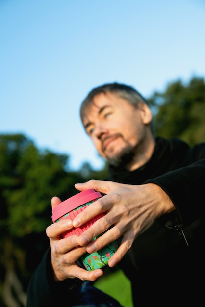 Hombre solitario, solo, de mediana edad tomando café en el parque. Concepto de soledad, distanciamiento social y autoafirmación. Concepto de salud mental, conexión con la naturaleza.