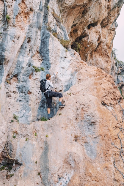 Foto hombre solo escalando con cuerda en un enorme acantilado en las montañas