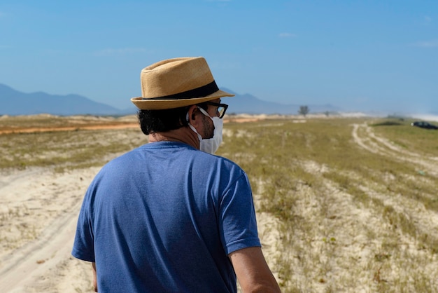 Hombre con sombrero caminando por una zona cercana a la playa