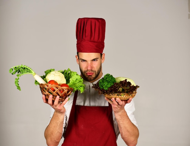 Hombre con sombrero de cocinero y delantal tiene ingredientes Comida vegetariana