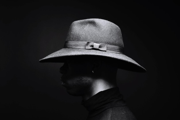 Foto hombre con sombrero contra un fondo negro