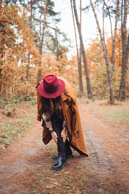 Un hombre con un sombrero rojo camina por un camino forestal con un árbol al fondo.