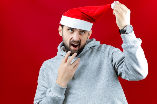 Un hombre con un sombrero rojo de Santa Claus con un estabilizador de imagen en sus manos en el que hay un teléfono lo sostiene con ambas manos y sonríe