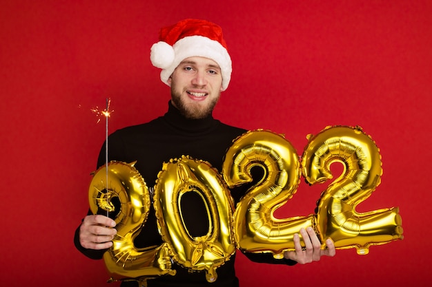 Un hombre con un sombrero de Santa Claus tiene los números 2022 y una bengala