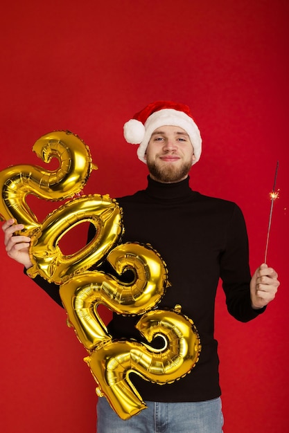 Un hombre con un sombrero de Santa Claus tiene los números 2022 y una bengala
