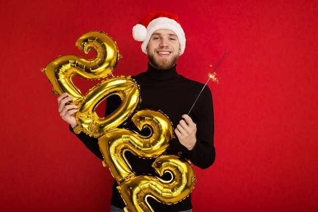 Un hombre con un sombrero de Santa Claus tiene los números 2022 y una bengala