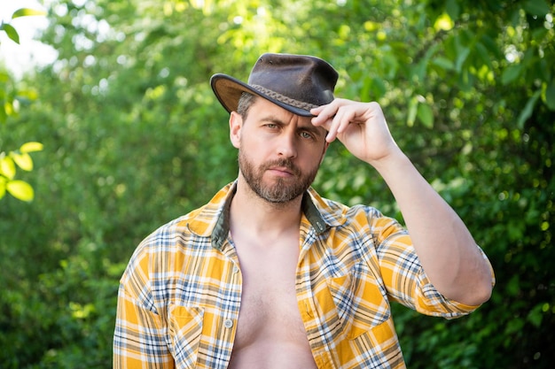 Hombre con sombrero de vaquero vaquero sexy en camisa a cuadros vaquero occidental con sombrero