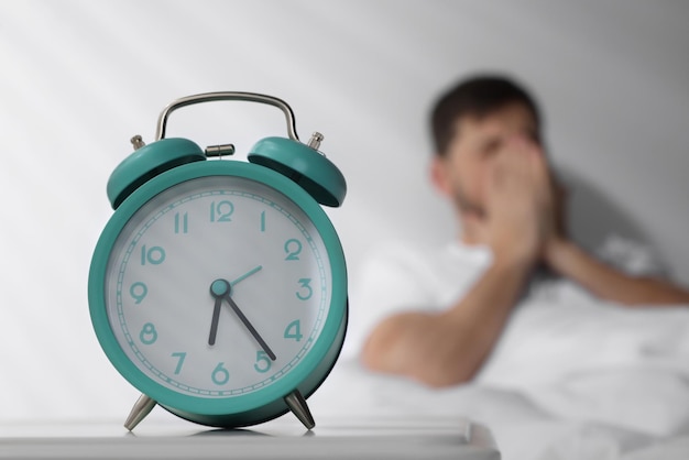 Hombre soñoliento despertándose en casa por la mañana concéntrese en el despertador Espacio para texto