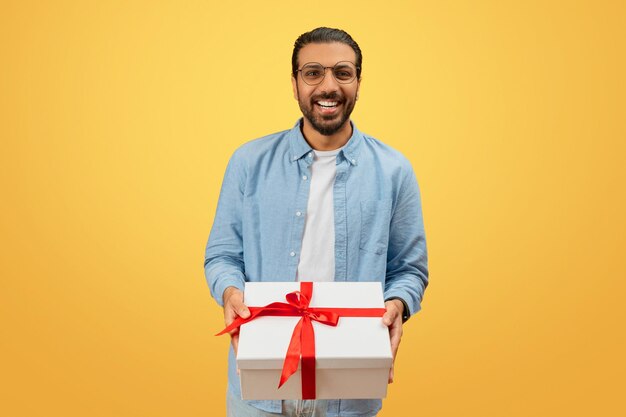 Hombre sonriendo con una caja de regalos blanca