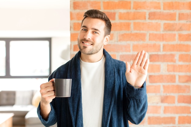 hombre sonriendo feliz y alegremente, saludando con la mano, dándote la bienvenida y saludándote, o diciéndote adiós