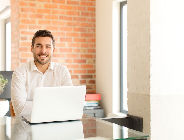 Hombre sonriendo felizmente con una mano en la cadera y actitud confiada, positiva, orgullosa y amistosa