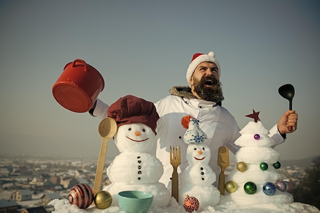 Hombre sonriendo con gorro de cocinero y uniforme el día de invierno.