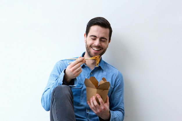 Hombre sonriendo con palillos y fideos