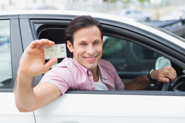 Foto hombre sonriendo y sosteniendo su licencia de conducir