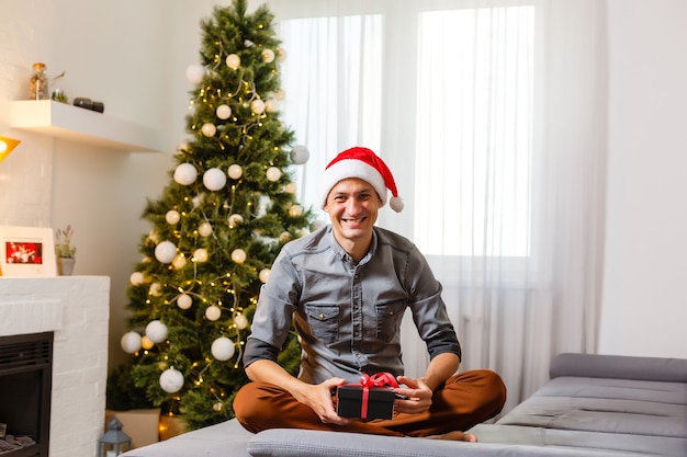 Hombre sonriente abriendo regalos de Navidad en casa