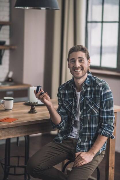 Hombre sonriente alegre sosteniendo una caja de anillo de bodas